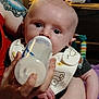 Braxton is registered to the contest to win money with this photo: baby, bottle, feeding, bib, infant, hand, tattoo, adult, arm, closeup, indoor, toy, clock, person, cute, child, feeding_time, nurturing, expression, clothing