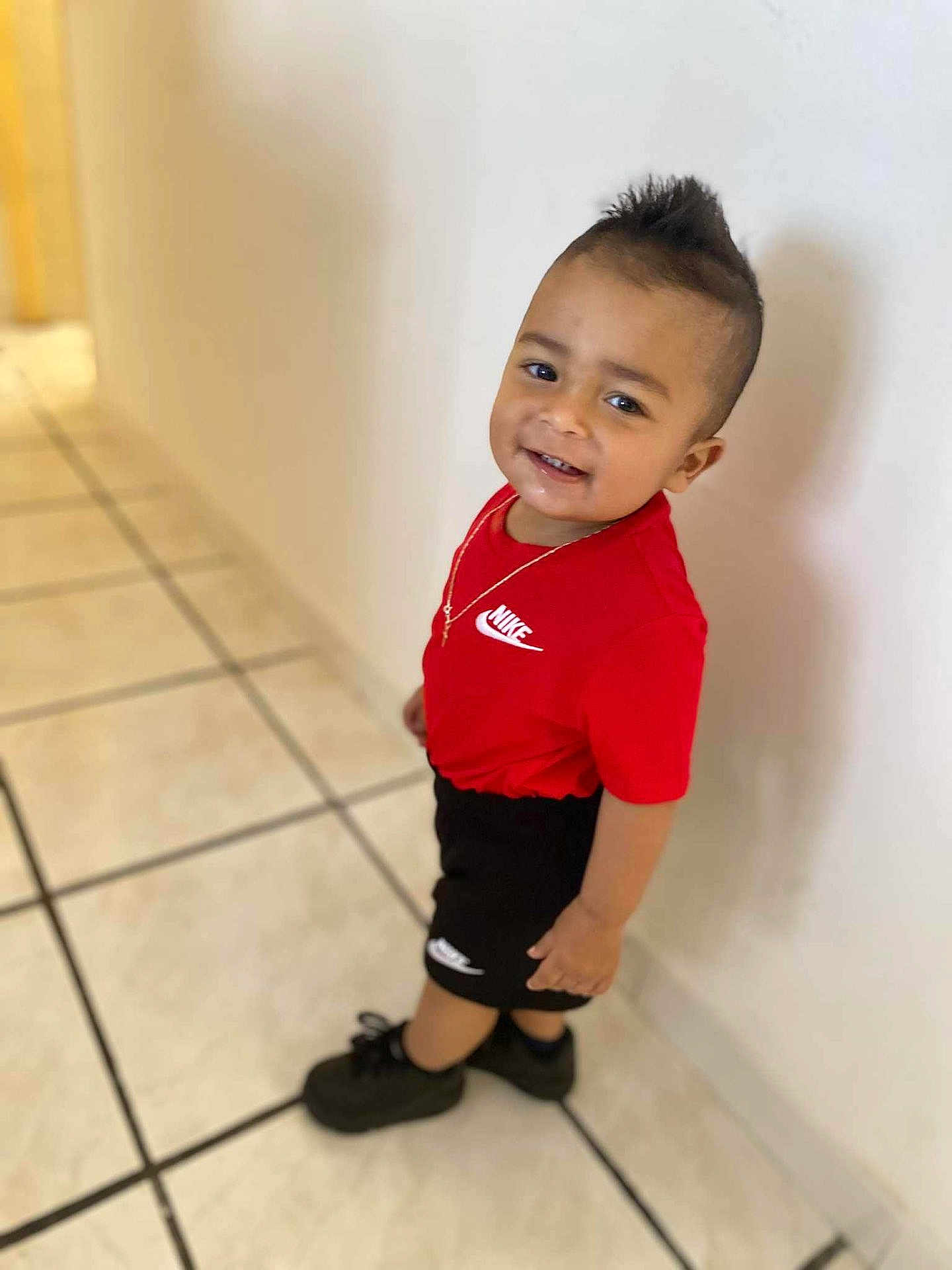 Djarown a rejoint le concours — aidez-le/la à gagner de superbes lots ! toddler, child, smiling, nike, red_shirt, black_shorts, mohawk, standing, indoor, tile_floor, white_wall, black_shoes, necklace, happy, person, casual_clothing, portrait, young_child, fashion, cute