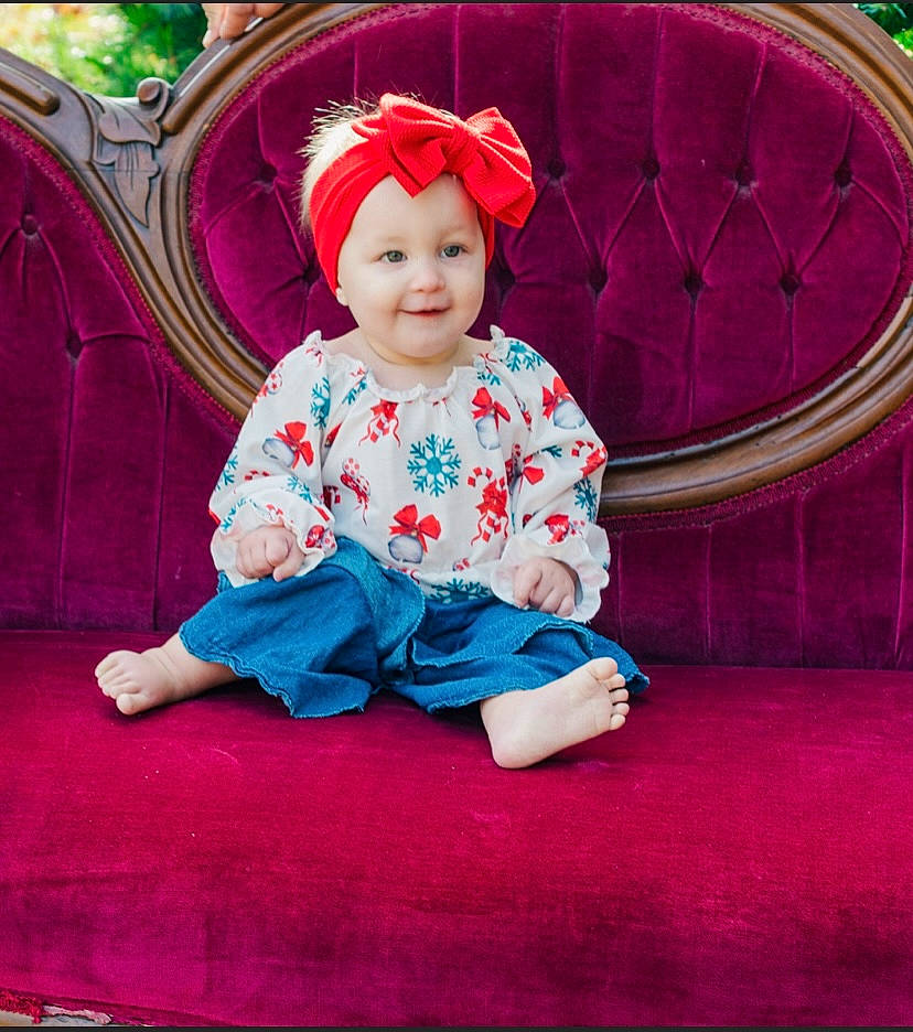 Hayden is registered to the contest to win money with this photo: baby, baby_toddler_clothing, child, costume_hat, electric_blue, face, fun, grass, happy, headwear, joy, leisure, magenta, pattern, person, pink, purple, sitting, sleeve, smile