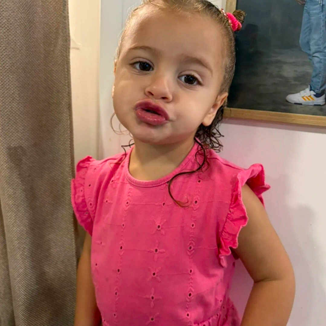 Yeimy a rejoint le concours — aidez-le/la à gagner de superbes lots ! child, childhood, curtain, cute, expression, fashion, framed_picture, girl, hair_buns, human, indoor, person, photograph, pink_dress, playful, portrait, posing, smile, wall, young