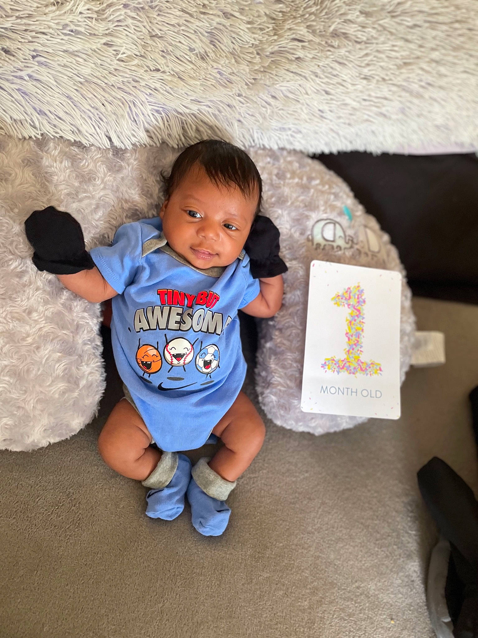 Zakai is registered to the contest to win money with this photo: arm, baby, baby_toddler_clothing, child, electric_blue, eye, finger, flooring, fun, happy, leisure, person, shirt, shorts, sitting, skin, sleeve, standing, t_shirt, toddler