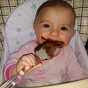 Inaya a rejoint le concours — aidez-le/la à gagner de superbes lots ! baby, child, high_chair, spatula, chocolate, face, messy, pink_clothing, stars, indoor, cute, smile, eating, happy, infant, person, toddler, closeup, hand, cooking