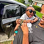 toddler, child, adult, sunglasses, smiling, laughing, outdoor, car, grass, house, person, holding, joyful, clothing, pacifier, accessory, happy, family, summer, casual