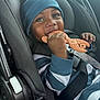 baby, child, car_seat, teether, wrench_shaped_toy, blue_hat, striped_clothing, smiling, happy, infant, safety_harness, seatbelt, hand, face, cute, indoor, closeup, person, headwear, chewing