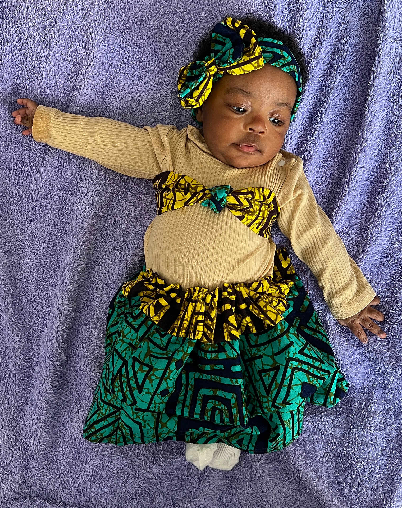 Lucimary a rejoint le concours — aidez-le/la à gagner de superbes lots ! baby, infant, child, headband, bow, skirt, patterned_fabric, purple_blanket, lying_down, portrait, cute, onesie, long_sleeve, hand, toes, gaze, cozy, textile, ruffled_waist, accessory