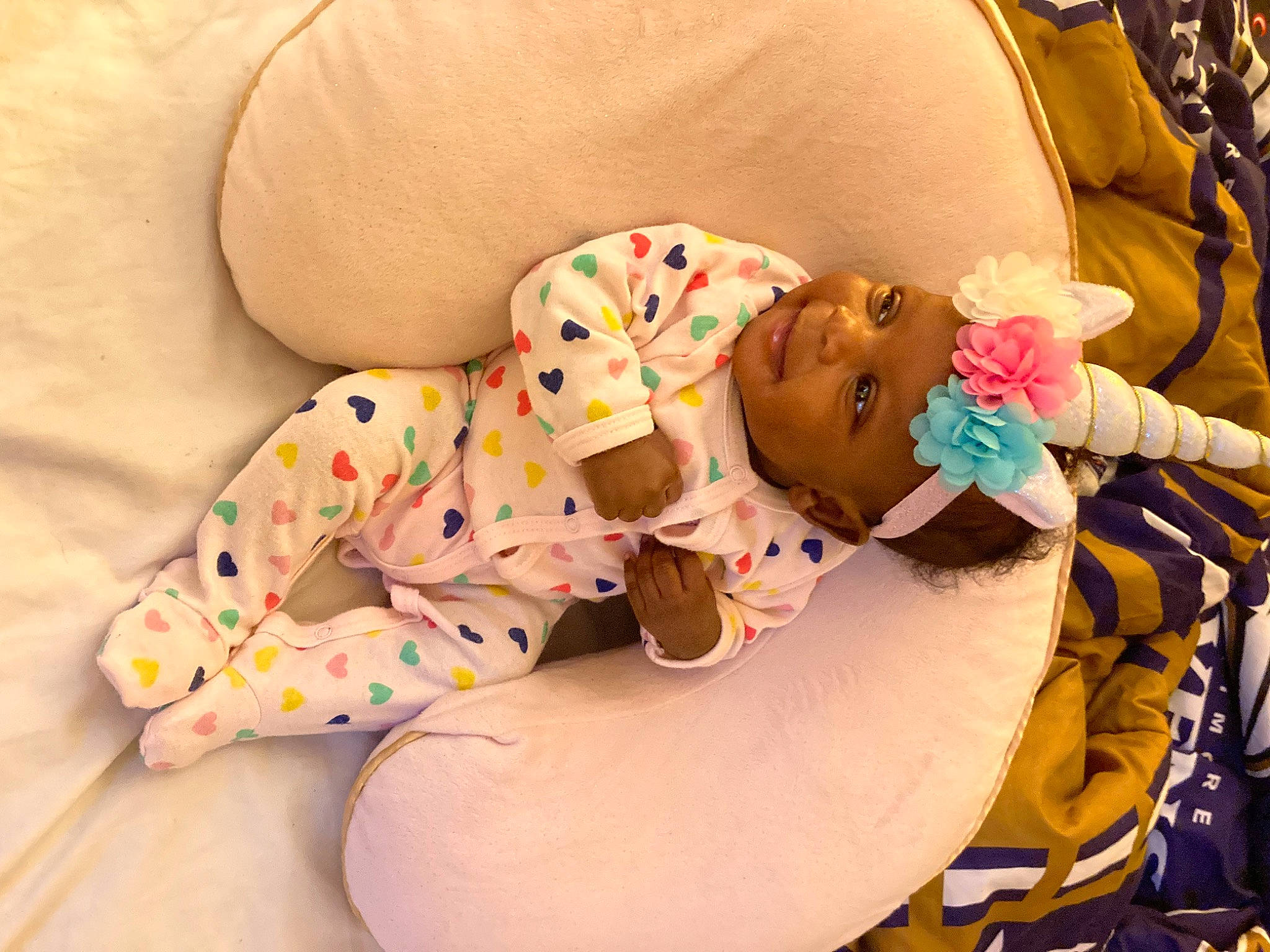 Ariyah is registered to the contest to win money with this photo: abdomen, arm, baby, baby_products, baby_sleeping, baby_toddler_clothing, cheek, child, comfort, headwear, human_body, human_leg, linens, pattern, person, sitting, skin, sleeve, stomach, textile