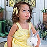 child, girl, yellow_dress, curly_hair, bow, rabbit, pet, spring, flowers, wreath, eggs, door, indoor, portrait, cute, animal, nature, decor, smiling, happy