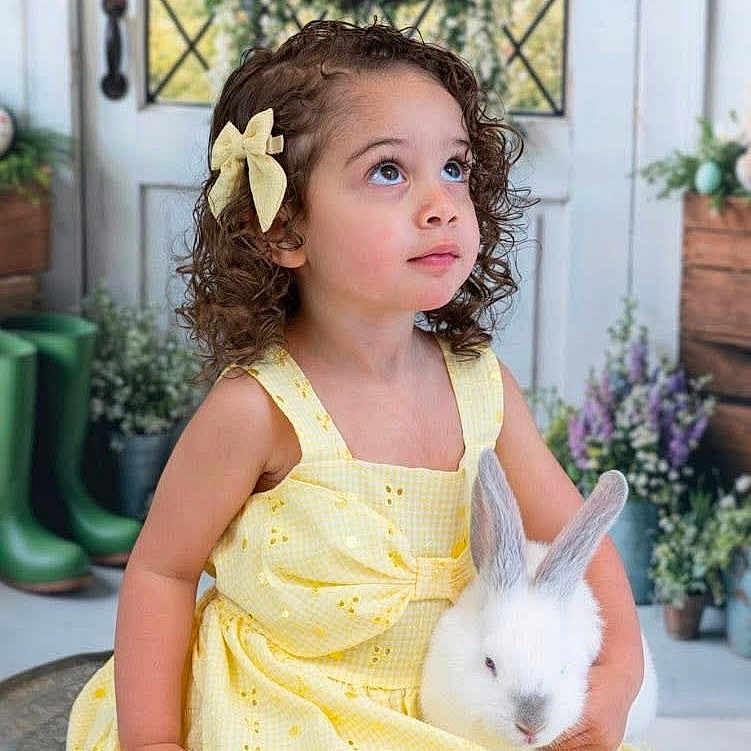Isabella joined the competition — help win amazing prizes! child, girl, yellow_dress, curly_hair, bow, rabbit, pet, spring, flowers, wreath, eggs, door, indoor, portrait, cute, animal, nature, decor, smiling, happy