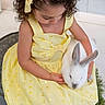 child, girl, rabbit, yellow_dress, bow, curly_hair, pet, animal, cute, spring, garden, flowers, white_rabbit, sitting, adorable, young_child, portrait, outdoor, nature, tender_moment