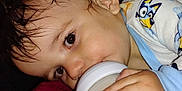 Skylar is registered to the contest to win money with this photo: baby, bottle, drinking, closeup, face, hand, pajamas, cartoon_character, child, infant, sleepwear, cute, person, skin, eyelashes, hair, indoors, soft_surface, holding, young_child