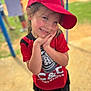 child, smiling, red_cap, red_shirt, outdoor, playground, grass, dirt, person, cute, happy, young, portrait, casual_clothing, summer, fun, nature, daylight, headwear, standing