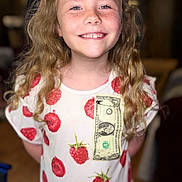Willow is registered to the contest to win money with this photo: child, smiling, freckles, blonde_hair, curly_hair, tshirt, raspberry_pattern, dollar_bill, indoor, portrait, happy, person, face, casual_clothing, young, cute, standing, childhood, fashion, closeup