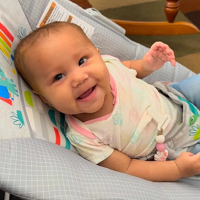 Kaylani is registered to the contest to win money with this photo: baby, babylaughing, chair, clothing, cushion, face, furniture, happy, head, homedecor, newborn, pants, person, photography, portrait, quilt, smile, t_shirt