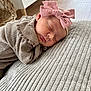 baby, sleeping, headband, pink_bow, knitted_clothing, blanket, texture, wicker_basket, wooden_floor, indoors, soft_lighting, peaceful, infant, closeup, resting, cozy, portrait, child, cute, calm