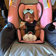 Harlo is registered to the contest to win money with this photo: baby, infant, car_seat, sleeping, bow, headband, pink, gray, socks, straps, child, cute, indoors, face, small_hands, baby_clothes, seat, resting, newborn, peaceful
