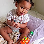 Kataleya joined the competition — help win amazing prizes! toddler, child, bed, blanket, pillow, lipton, bottle, hair_clip, curly_hair, white_wall, indoor, diaper, tshirt, sitting, cross_legged, soft_texture, curious_expression, natural_light, cozy, young_child