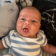 Ayden a rejoint le concours — aidez-le/la à gagner de superbes lots ! baby, infant, child, striped_onesie, blanket, soft_fabric, face, head, mouth_open, cute, lying_down, skin, cheeks, expression, young, person, indoors, sleepwear, comfort, resting