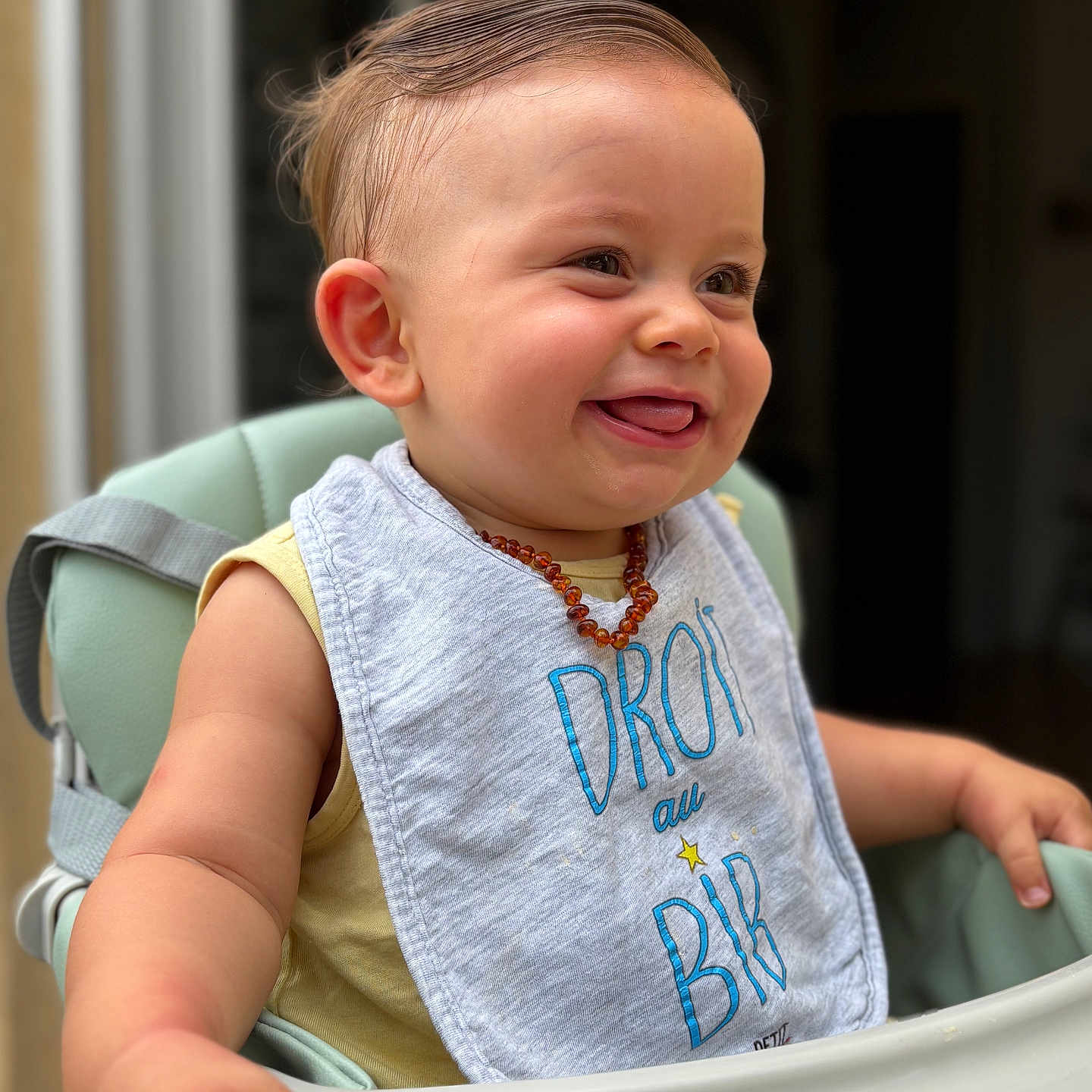 Ayden a rejoint le concours — aidez-le/la à gagner de superbes lots ! arm, baby, bib, child, close_up, clothing, cute, face, happy, head, high_chair, indoor, infant, necklace, person, seat, skin, smile, tongue_out, young_child