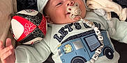 Ayden a rejoint le concours — aidez-le/la à gagner de superbes lots ! baby, ball, bed, blanket, child, clothing, comfort, cute, happy, hood, indoor, infant, lying_down, pacifier, person, plush_toy, smiling, soft, sweatshirt, toy