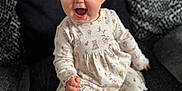 Darcie-Mae joined the competition — help win amazing prizes! baby, child, smiling, sitting, dress, bow, couch, footwear, happy, indoor, portrait, infant, cute, clothing, sock, patterned, furniture, expression, headwear, person