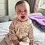 Darcie-Mae is registered to the contest to win money with this photo: baby, child, pajamas, smiling, happy, sitting, bed, blanket, indoors, cute, face, hands, feet, clothing, portrait, natural_light, cozy, infant, person, home