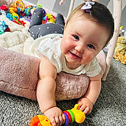 Darcie-Mae joined the competition — help win amazing prizes! baby, child, toy, giraffe_toy, cushion, carpet, smile, face, hand, clothing, indoor, playtime, cute, purple_bow, cheeks, person, toddler, colorful, soft, happy