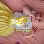 Luna is registered to the contest to win money with this photo: baby, infant, yellow_skirt, white_shirt, winnie_the_pooh, lying_down, pink_background, clothing, child, cute, face, hand, thumb_sucking, infant_girl, portrait, soft_lighting, indoors, young_child, skin, expression