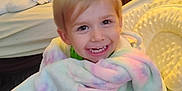 Draven is registered to the contest to win money with this photo: toddler, child, blanket, baby_chair, smiling, indoor, pastel_colors, face, happy, furniture, bed, pillow, toy, cozy, wrapped, young_child, cute, home, seated, portrait