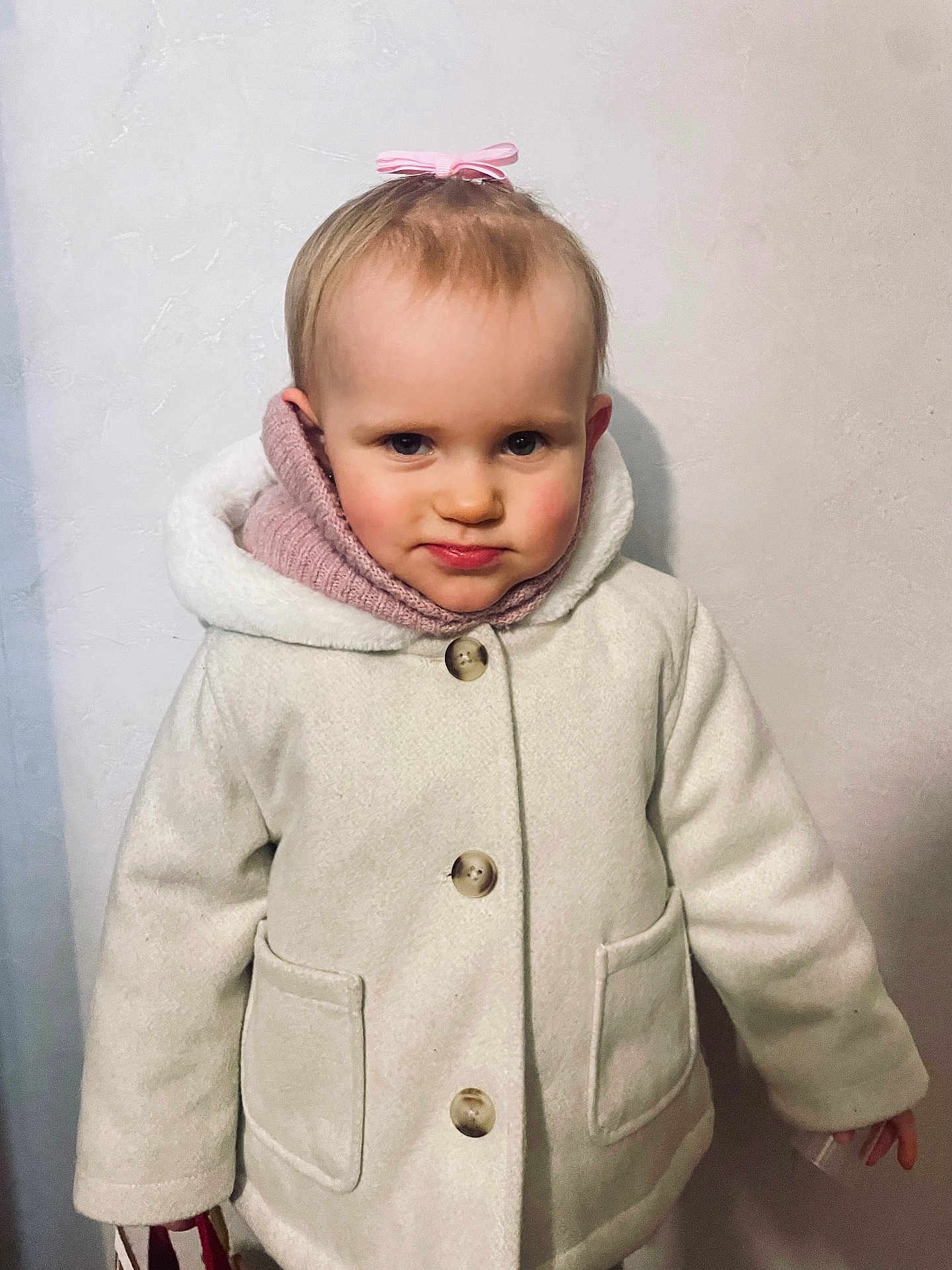 Victorya a rejoint le concours — aidez-le/la à gagner de superbes lots ! baby, buttons, child, coat, cute, expression, face, hair, head, indoor, looking_at_camera, person, pink_bow, pink_scarf, portrait, skin, standing, warm_clothing, white_coat, young_child
