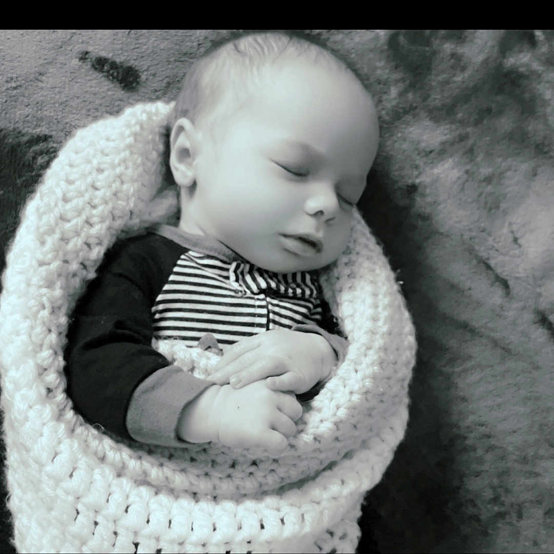Atles is registered to the contest to win money with this photo: baby, sleeping, blanket, knitted, infant, peaceful, black_and_white, portrait, hands, cute, cozy, child, soft_texture, resting, wrapped, newborn, face, closeup, indoor, calm