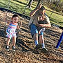 child, family, fun, grass, happy, man, outdoor, playground, playing, shoes, shorts, socks, striped_dress, summer, sunlight, swing, tattoo, toddler, trees, woodchips