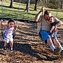 Harlee joined the competition — help win amazing prizes! child, toddler, man, swing, playground, outdoor, grass, trees, sunlight, smiling, happy, casual_clothing, summer, fun, family, tattoo, woodchips, blue_poles, footwear, park