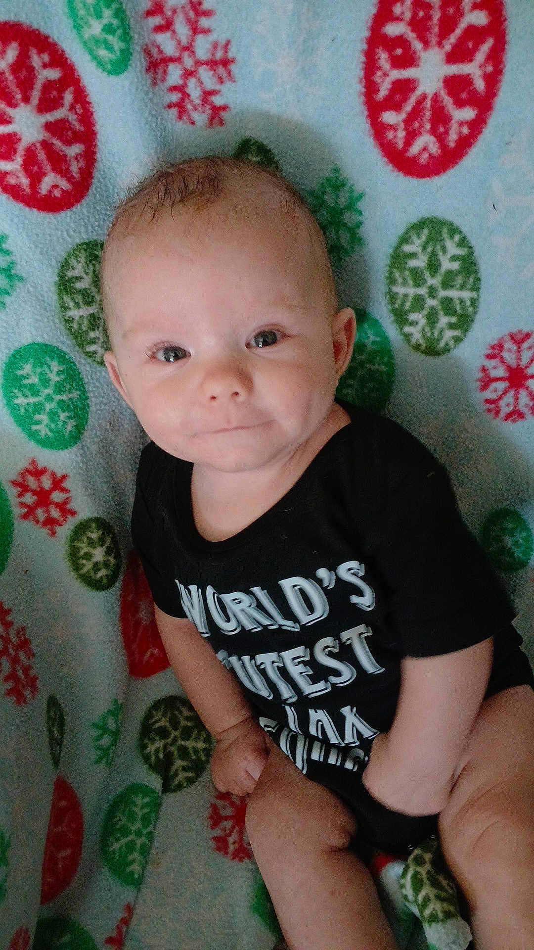 Charles Jaxson joined the competition — help win amazing prizes! baby, black_clothing, blanket, blue, child, cute, face, green, hand, head, indoors, infant, onesie, pattern, portrait, red, sitting, skin, smiling, snowflake
