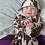 Charles Jaxson is registered to the contest to win money with this photo: baby, bed, child, cow_pattern, cozy, cute, fabric, face, hands, happy, hooded_onesie, indoor, infant, person, pillow, portrait, purple, smiling, white, young