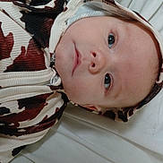 Charles Jaxson is registered to the contest to win money with this photo: baby, blanket, child, closeup, clothing, comfortable, cute, expressionless, eyes, face, hood, indoors, infant, lying_down, pattern, person, portrait, skin, soft, young