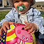 Luce participe au concours pour gagner de l'argent avec cette photo : baby, ball, child, clothing, cute, face, grass, hand, hat, outdoor, pacifier, peppa_pig, person, play, sitting, smile, striped_jacket, sunlight, toddler, toy