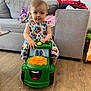 baby, child, colorful, couch, cute, dress, floor, floral, furniture, green, happy, indoor, living_room, person, play, smiling_toy, toddler, toy, tractor, wooden_floor