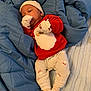 baby, infant, blanket, blue_blanket, red_sweater, santa_claus, mittens, hat, white_pants, socks, lying_down, indoors, cute, holiday_theme, soft_texture, warm_clothing, newborn, resting, portrait, cozy