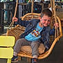 Noah a rejoint le concours — aidez-le/la à gagner de superbes lots ! child, boy, swing, indoor, denim_jacket, paw_patrol_tshirt, sneakers, yellow_chair, cafe, window, rope, wooden_swing, smile, playful, person, modern_interior, plant, table, people, seating