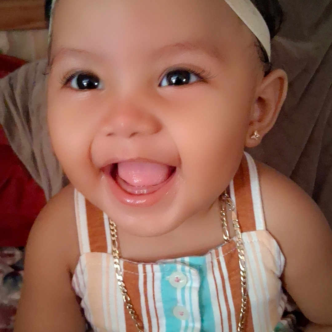 Novanny Charles is registered to the contest to win money with this photo: baby, bow, child, closeup, cute, dress, earrings, face, hand, happy, headband, indoors, jewelry, necklace, person, portrait, skin, smiling, striped_clothing, young_child