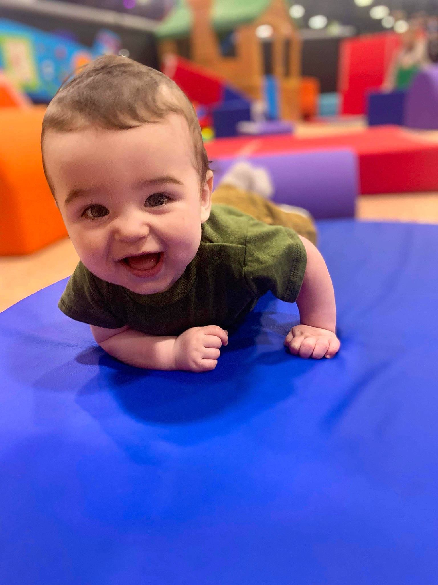 Greyson is registered to the contest to win money with this photo: baby, blue, child, competition_event, electric_blue, facial_expression, flooring, fun, games, happy, human_body, indoor_games_and_sports, leisure, person, play, recreation, room, sitting, smile, sports