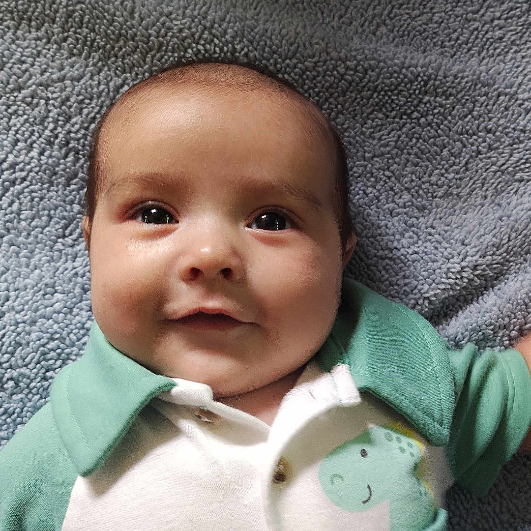 Elijah joined the competition — help win amazing prizes! baby, infant, smile, face, child, cute, dinosaur, clothing, blanket, green, white, soft_texture, lying_down, portrait, young_child, happy, indoors, cozy, toddler, apparel