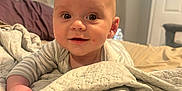 Kolten is registered to the contest to win money with this photo: baby, infant, bed, blanket, quilt, smiling, face, eyes, hand, indoors, curious, cute, cozy, sleepwear, person, portrait, head, skin, expression, resting
