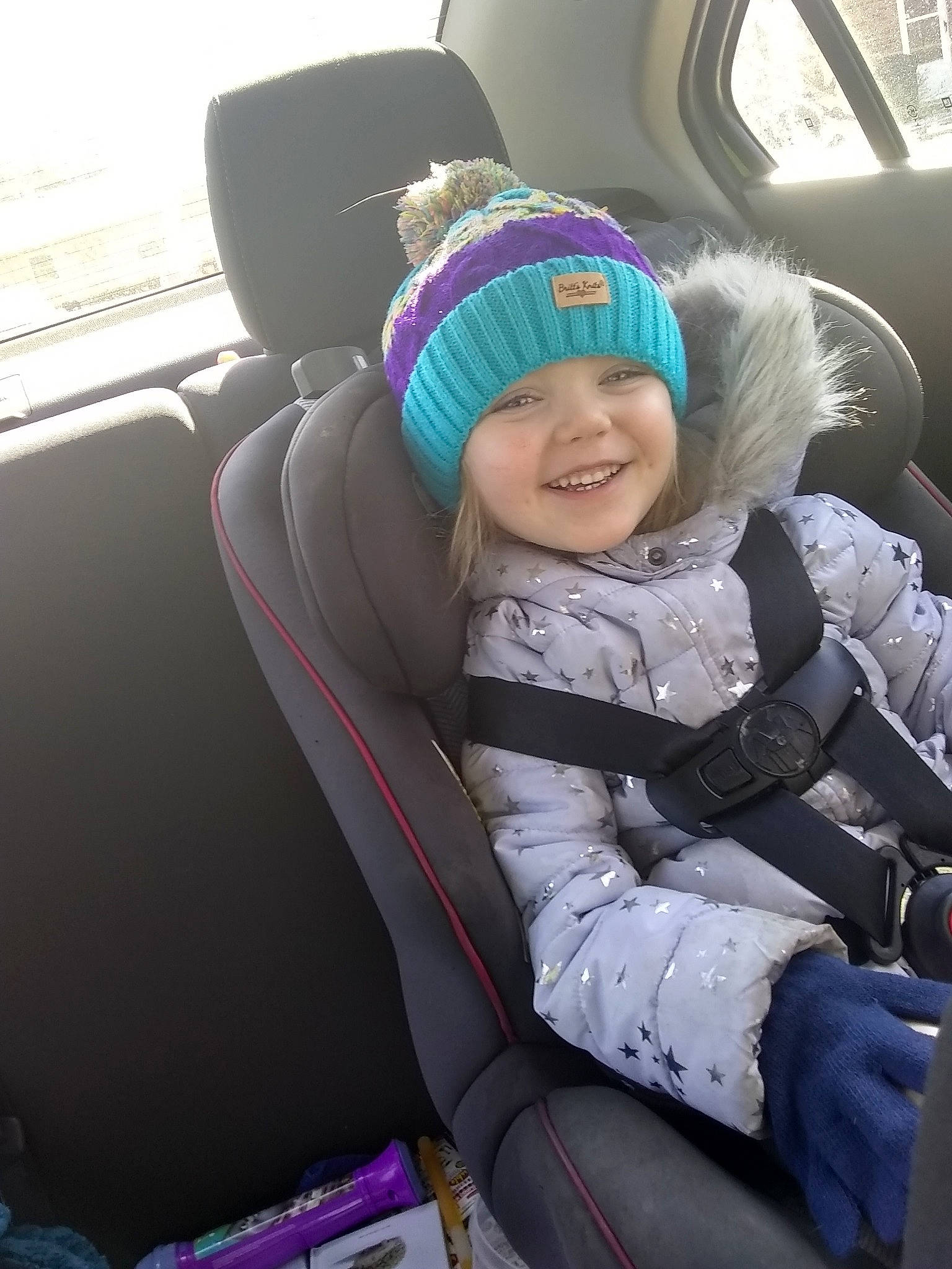 Saria is registered to the contest to win money with this photo: auto_part, baby, baby_in_car_seat, beanie, bonnet, car, car_seat, car_seat_cover, child, city_car, family_car, head_restraint, headgear, joy, knit_cap, person, smile, snow, toddler, vacation