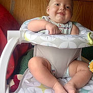 Trenton is registered to the contest to win money with this photo: baby, smiling, infant, baby_seat, fisher_price, blanket, wood_paneling, can, spaghetti_rings, baby_bottle, toy, feet, legs, hand, clothing, indoor, face, cute, child, seated