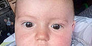 Trenton is registered to the contest to win money with this photo: baby, child, face, eyes, chubby_cheeks, onesie, indoor, close_up, curious, infant, person, cute, expression, portrait, clothing, young_child, head, skin, pink_cheeks, looking