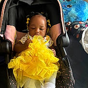 Brooklynne joined the competition — help win amazing prizes! baby, blanket, car_seat, child, clothing, cute, decor, fabric, footwear, hair_accessories, indoor, infant, plush_pillow, portrait, relaxed, sitting, toy, white_socks, yellow_dress, young_child