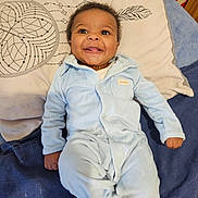 Makan a rejoint le concours — aidez-le/la à gagner de superbes lots ! baby, infant, child, smile, happy, pajamas, blue_pajamas, onesie, pillow, bedding, blanket, lying_down, face, eyes, hands, feet, amber_necklace, indoor, portrait, cute