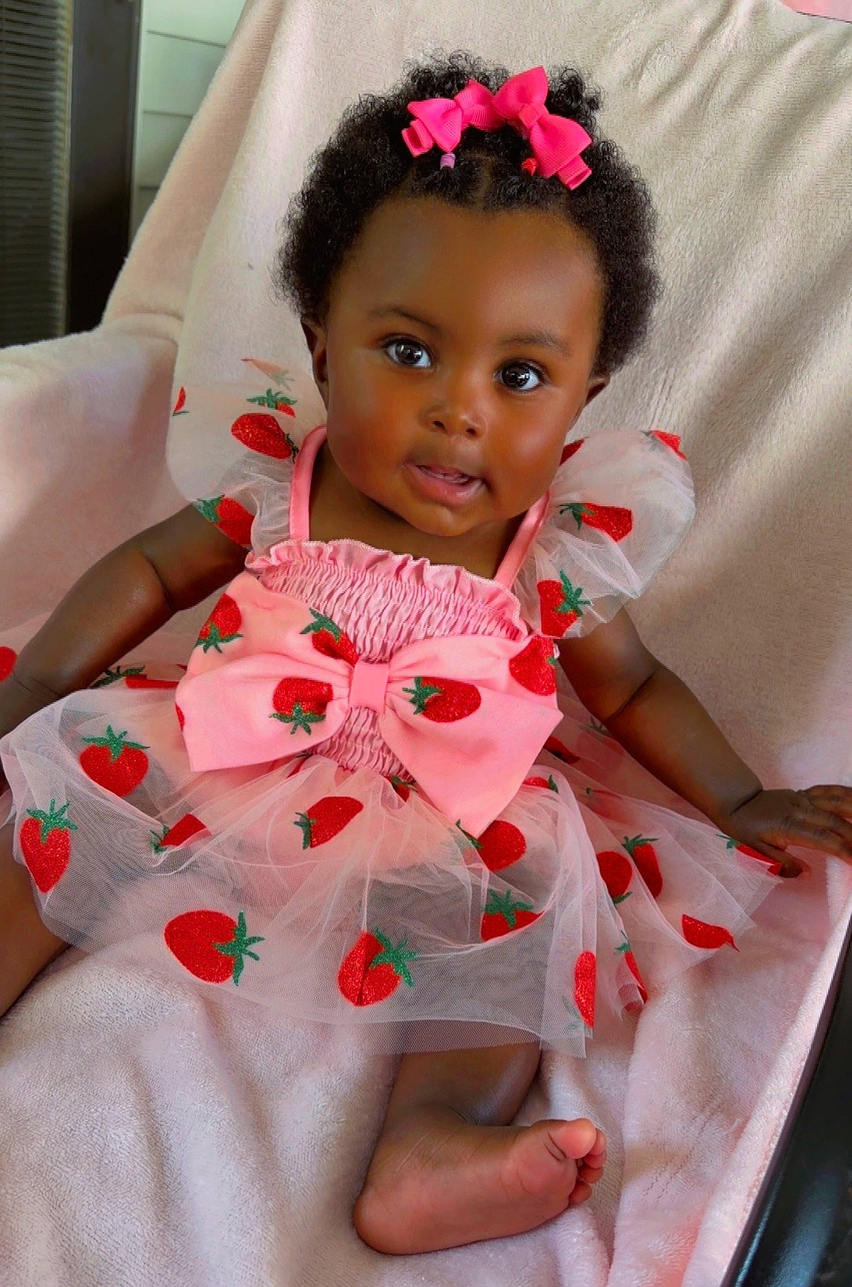 Jream is registered to the contest to win money with this photo: adorable, baby, blanket, child, closeup, curly_hair, cute, dress, fashion, girl, happy, indoors, person, pink_bow, portrait, sitting, smiling, soft_texture, strawberry_pattern, toddler