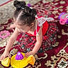 child, toddler, girl, portrait, playtime, toy, shape_sorter, colorful, dress, hair_buns, brown_hair, sitting, indoors, rug, patterned_carpet, focused, playing, children_toy, home, safe